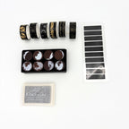 Six rolls of black and gold celestial washi tape, a moon phase wooden stamp set and silver craft ink pad with black annotation tags