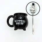 Witches brew cauldron mug in black with a crescent moon, shown with the silver spoon stamped stirring up a little magic