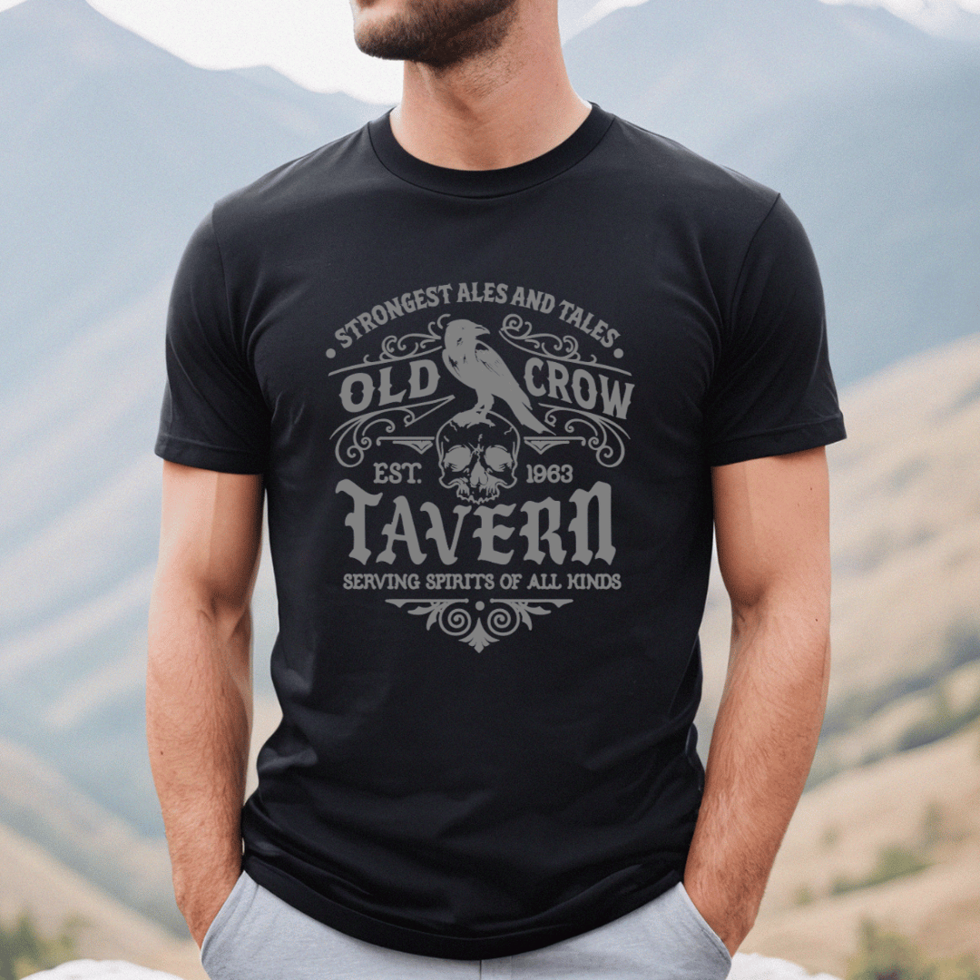 Person wearing a black t-shirt with 'Old Crow Tavern' design against a mountainous background