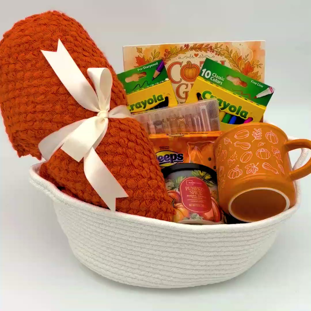Video of the fall coloring gift basket with an orange knit throw blanket, coloring book, pumpkin mug, candle, and coloring supplies
