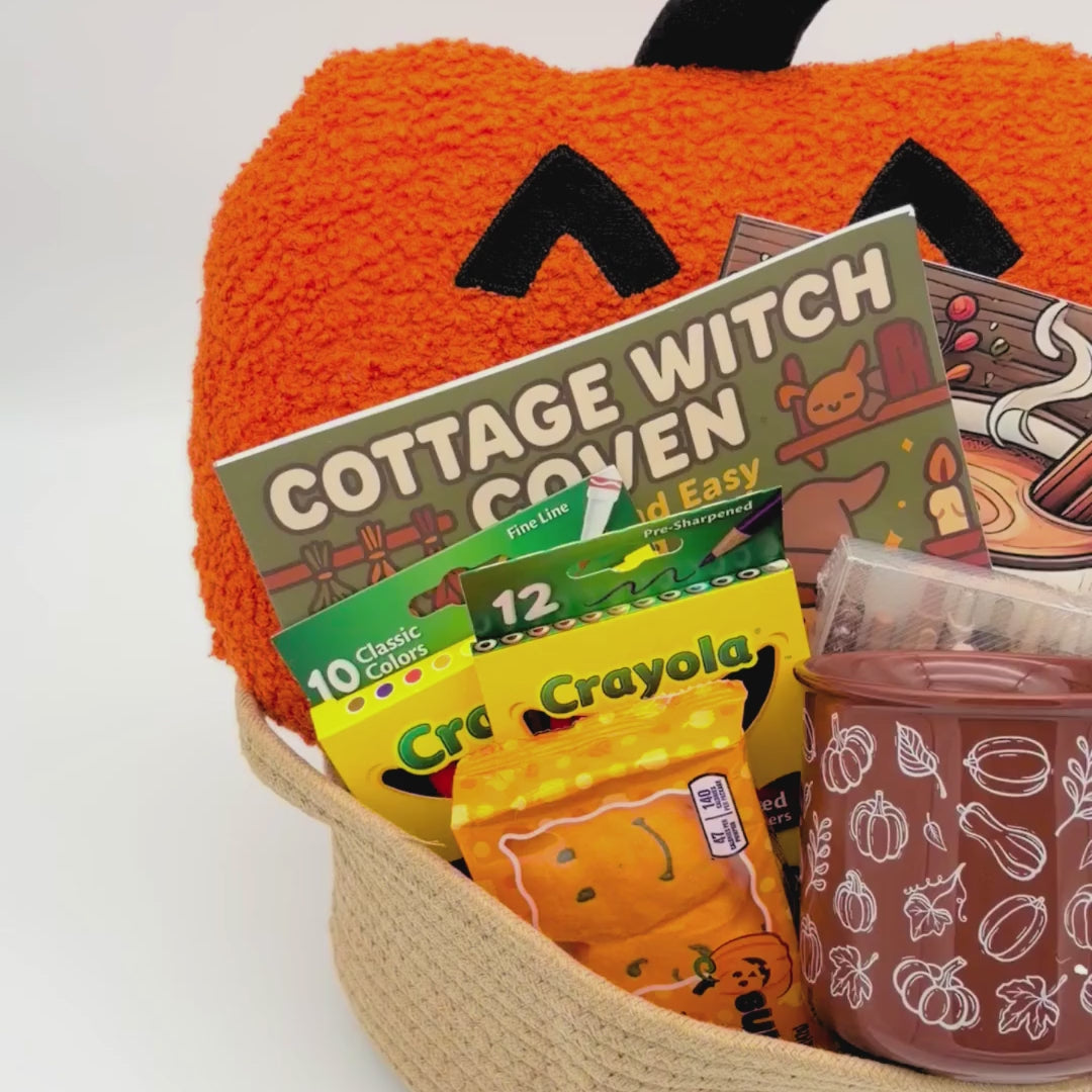 Video of the jack-o'-lantern coloring book gift set with a pumpkin pillow, cottage witch coloring book, markers, and brown mug