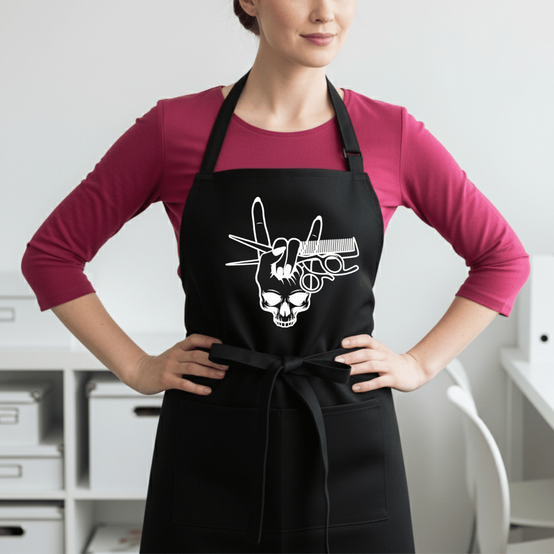 Black professional stylist apron with white skull, rock gesture with feminine nails and styling tools worn by female stylist