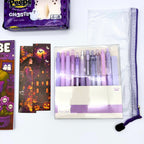 Halloween bookmarks with a witch and a haunted house beside a lilac gel pen set, clear mesh zipper pouch, and marshmallow ghosts