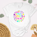 A white short-sleeve t-shirt with a colorful graphic that reads 'TALK CRAFTY TO ME' surrounded by craft-themed illustrations, styled in a flat-lay design.