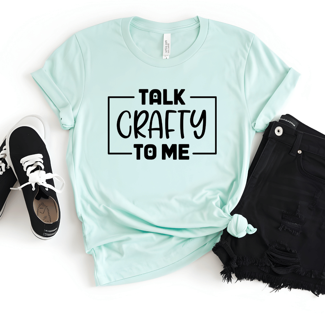 Mint green t-shirt with 'Talk Crafty to Me' text, paired with black sneakers and shorts on a white background
