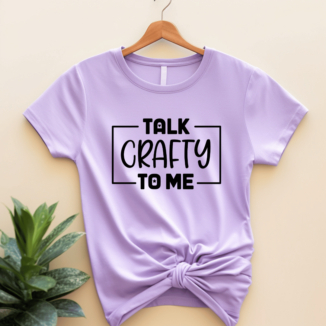 Purple lilac t-shirt with 'Talk Crafty to Me' text on a hanger against a beige background