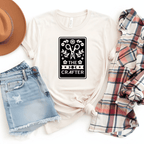 The Crafter tarot card t-shirt in natural tan with scissors, botanicals, and moon phase design