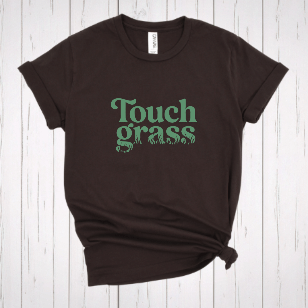 Touch Grass funny internet humor t-shirt with retro serif font and grass blade lettering on a dark brown shirt