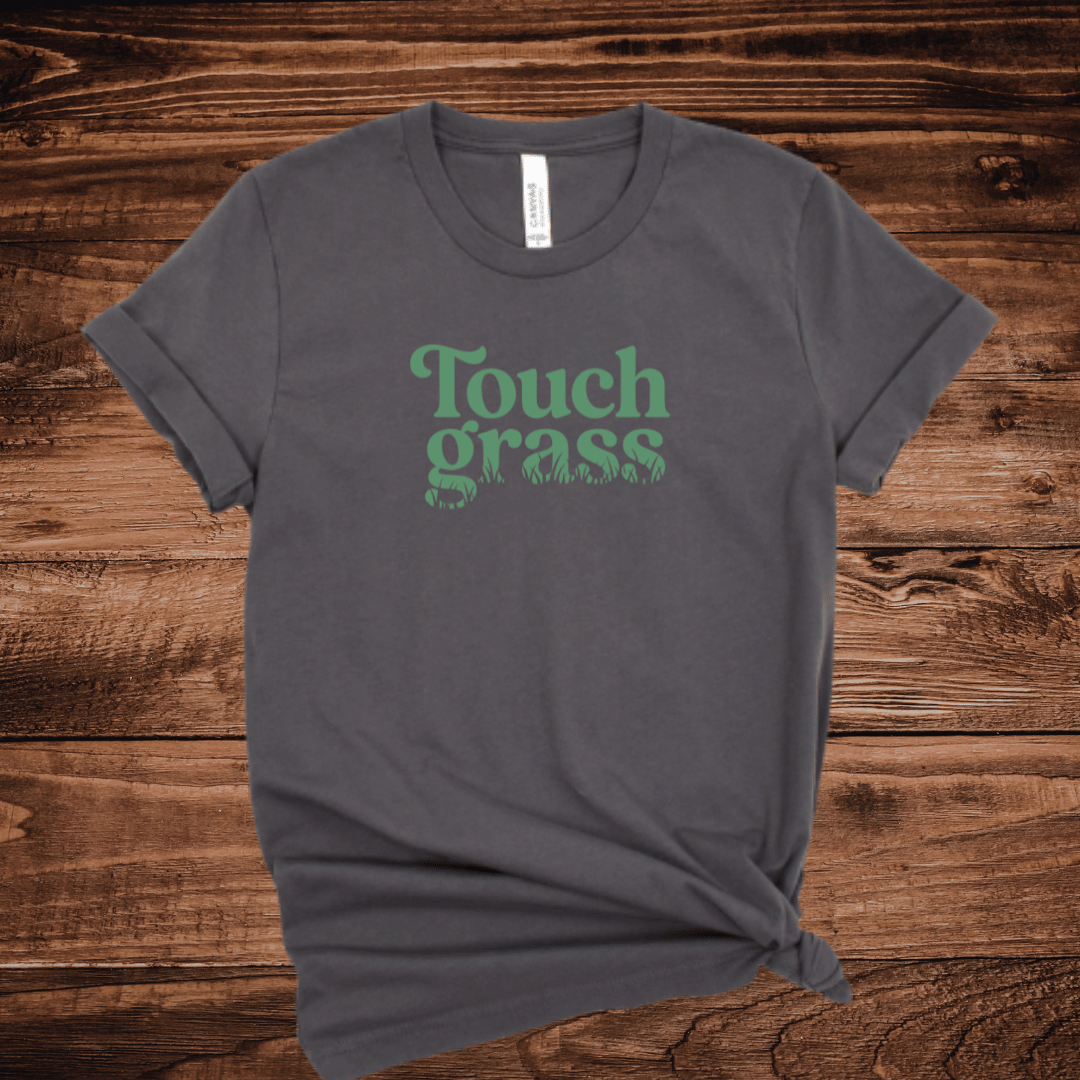 Touch Grass funny meme t-shirt with retro serif font and grass blade lettering on a dark gray shirt