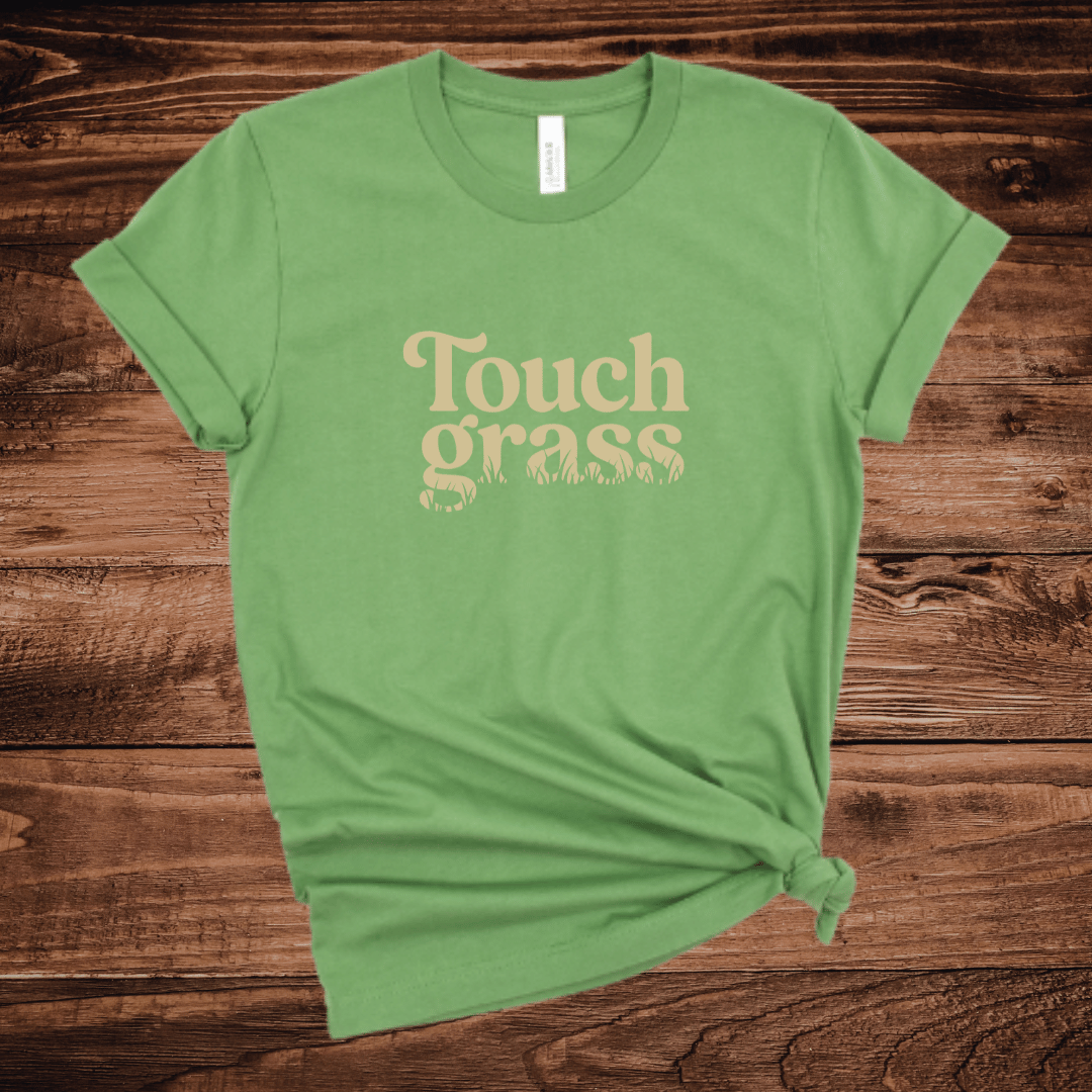 Touch Grass funny outdoor t-shirt with retro serif font and grass blade lettering on a leaf green shirt