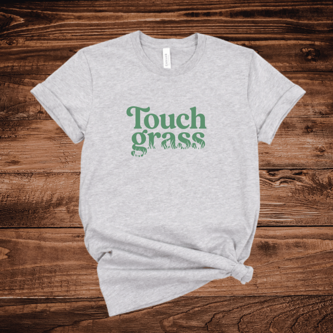 Touch Grass funny internet meme t-shirt with retro serif font and grass blade lettering on a light gray shirt