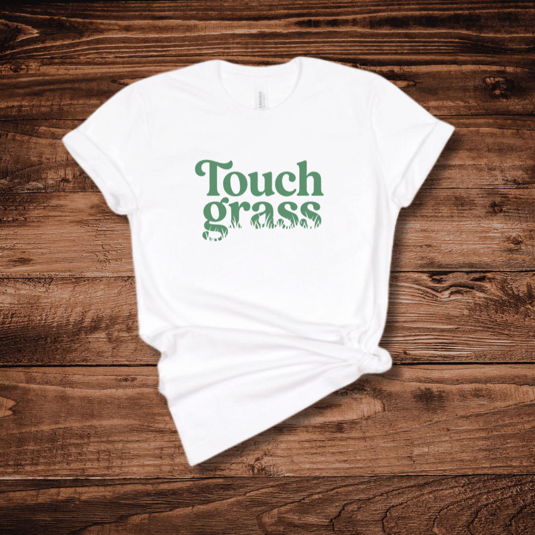 Touch Grass funny internet humor t-shirt with retro serif font and grass blade lettering on a white shirt